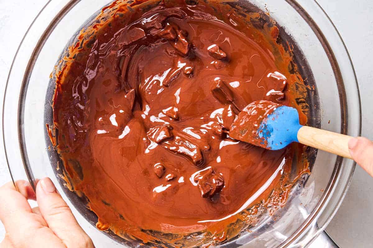 An overhead close up photo of the chocolate for the flourless chocolate cake being melted in a bowl over a pot of simmering water.