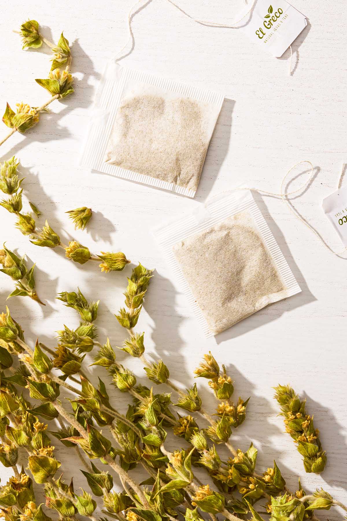 An overhead photo of a bunch of Greek mountain tea and 2 unwrapped bags of the tea.