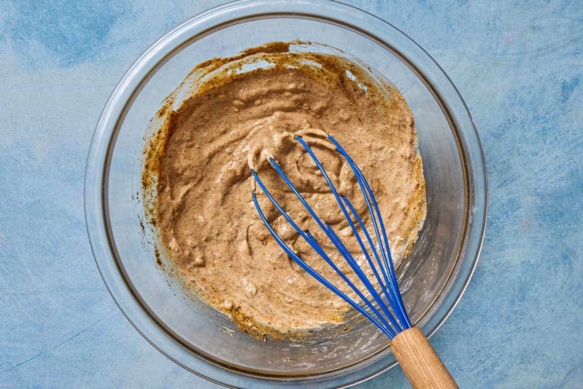 An overhead photo of chicken marinated being whisked in a mixing bowl.