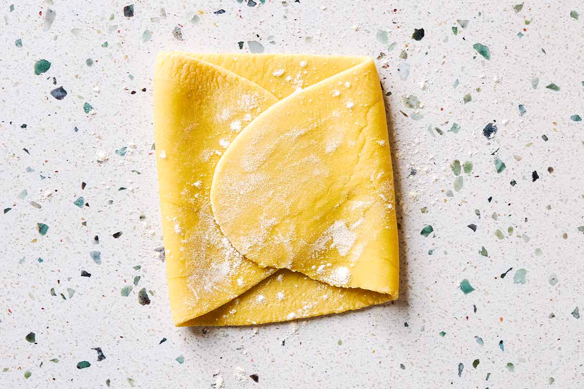 A close up a folded sheet of uncooked homemade pasta.