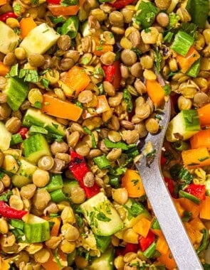 A close up of lentil salad in a serving bowl with a spoon.