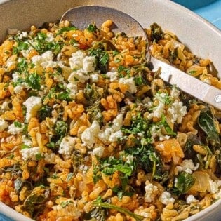 Spanakorizo in a serving bowl with a serving spoon.