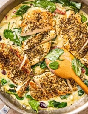 Sun Dried tomato chicken in a skillet with a wooden spoon.