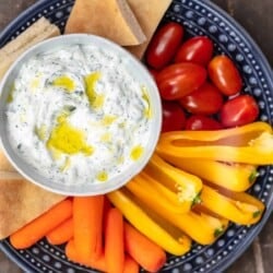 Tzatziki sauce with vegetables and pita wedges on a platter