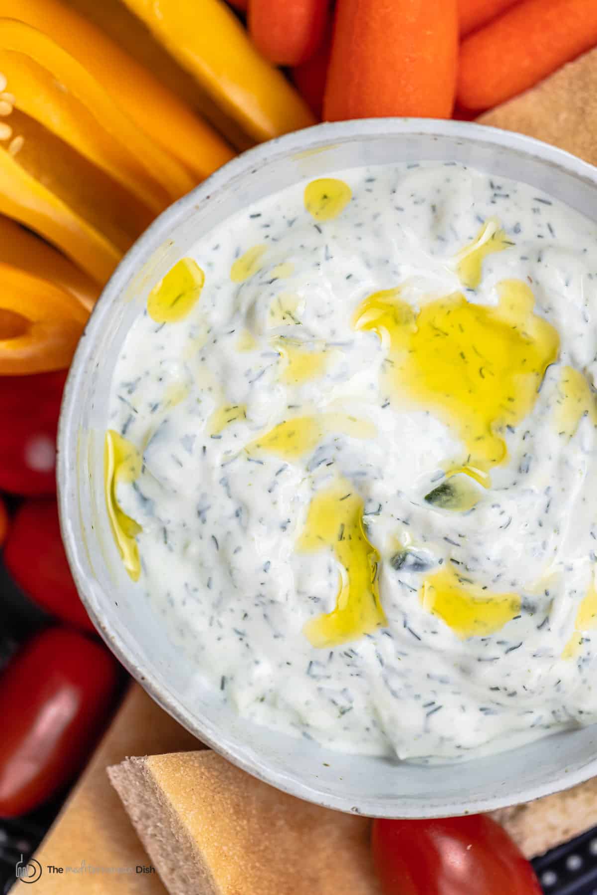 Tzatziki cucumber yogurt sauce in a bowl with a side of sliced vegetables