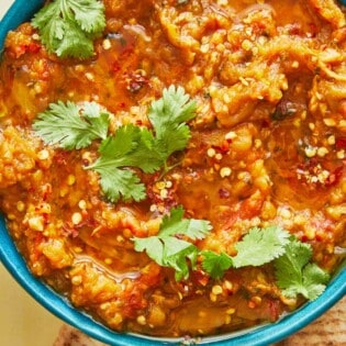 zaalouk (Moroccan cooked eggplant salad) in a blue bowl with a cilantro garnish.